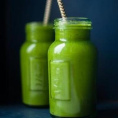 Several green smoothies against sunny background