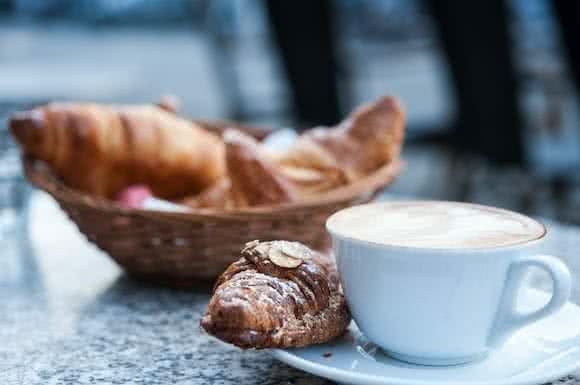 Saure Lebensmittel wie Croissant und Kaffee mit Milch